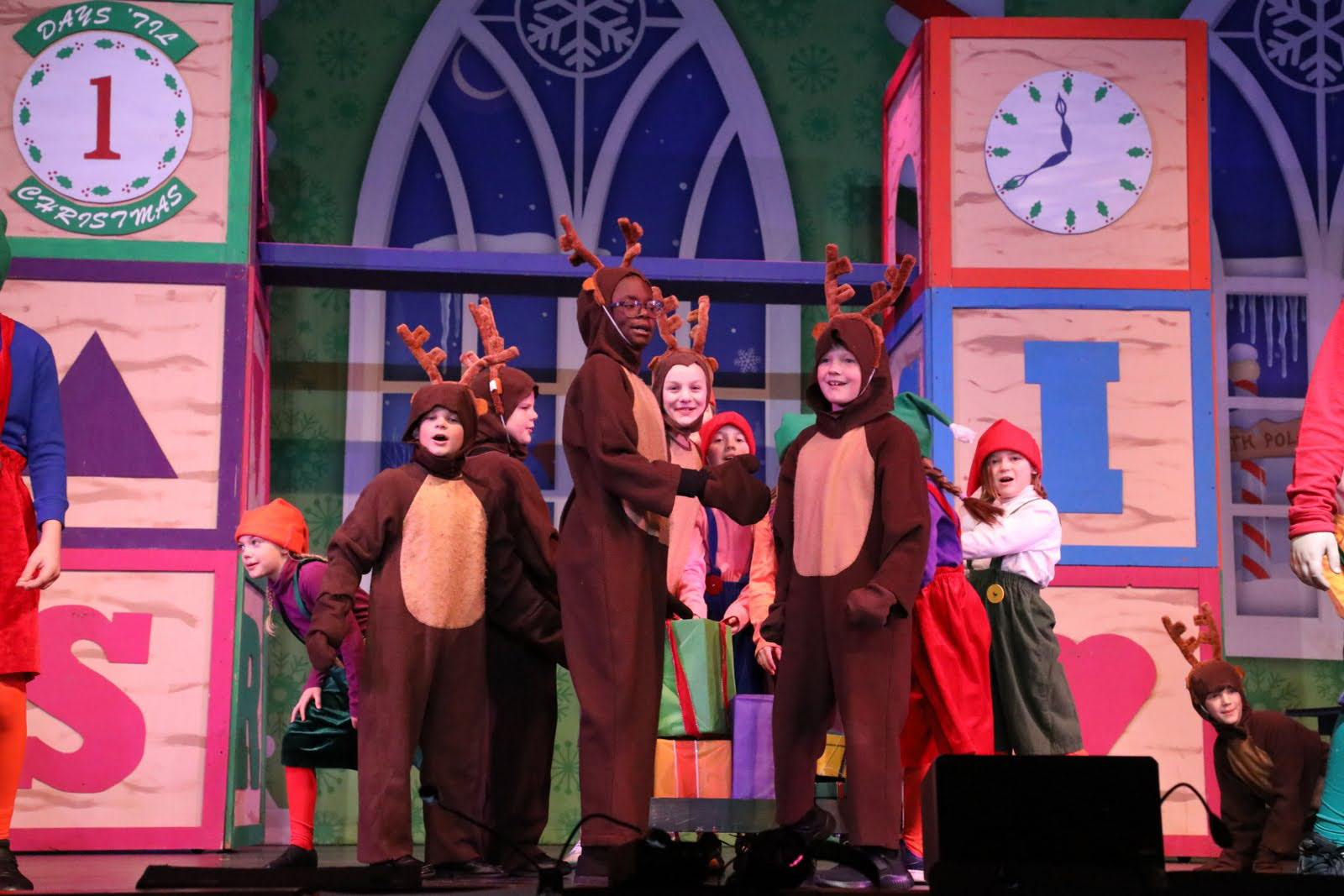 Children dressed as elves and reindeer in Santa's workshop featuring oversized blocks.